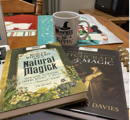 Two books titled Modern Witchcraft Book of Natural Magick and Witchcraft and Magic, as well as a mug with the words Witches be sippen.